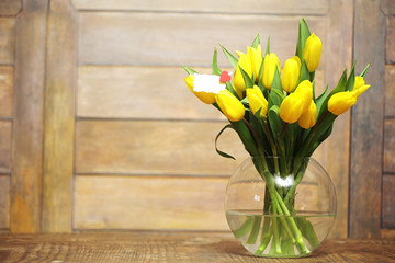 A bouquet of yellow tulips in a vase on the floor. A gift to a w