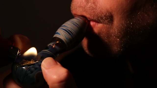 Man smoke marijuana from pipe bowl