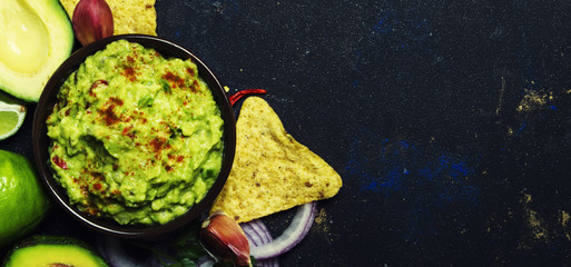 Mexican food, guacamole sauce with avocado, onion, garlic and chili, black background, top view