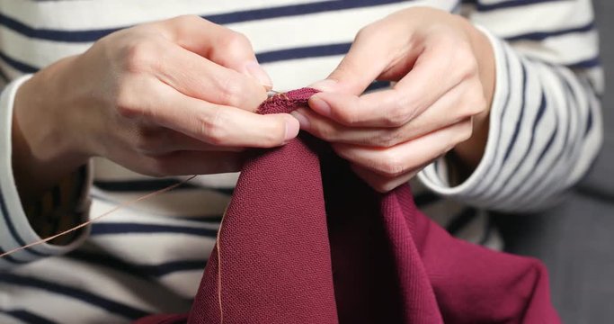 Woman Sews with a needle and thread