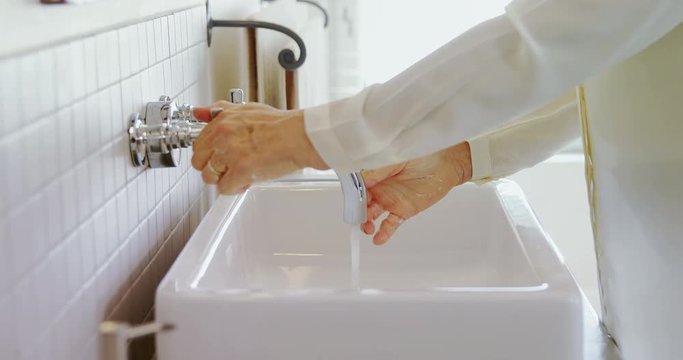 Senior woman washing her hands in sink 