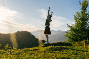 a woman tourist stands on a background of green forest and high mountains