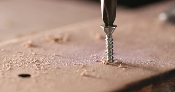 Craftsman drives the screw into the wooden board