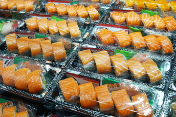 Selective focus on salmon sushi box. Salmon sushi in takeaway box ready for sale in restaurant. Sushi box with wasabi and ginger for hurry meal. Salmon sushi box cook in asian style