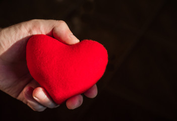Man hands holding a heart on black background