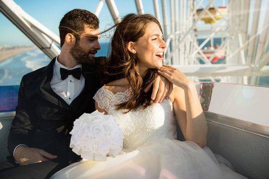 Happy lifestyle enthusiastic excited just married couple in wedding dress and tuxedo on theme park ride