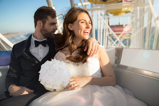 Bride and groom destination wedding ride ferris wheel enjoying sunset over beach