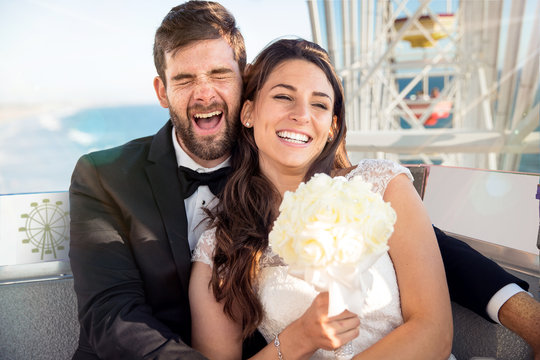 Cute fun bride and groom enjoying honeymoon lifestyle destination wedding on ferris wheel
