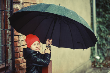 Boy with an umbrella walking in the city