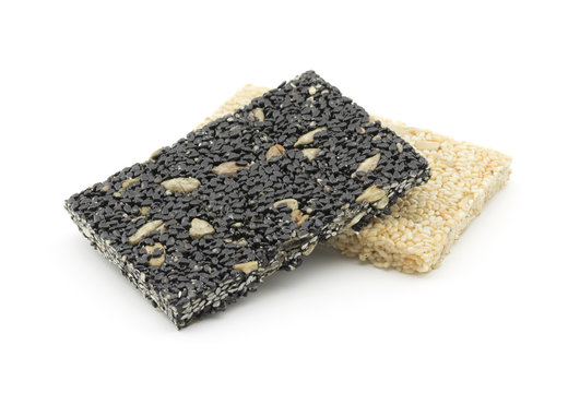 pile of sesame seeds with sunflower kernels bar on white background
