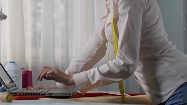 Tailor woman choosing design colors on laptop, order coordination with customer