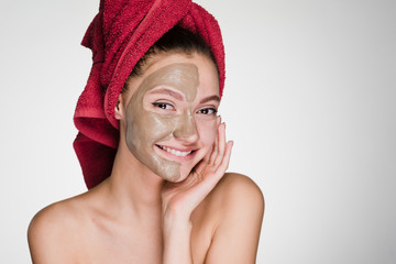 happy woman with a towel on her head apply a cleansing mask on her face