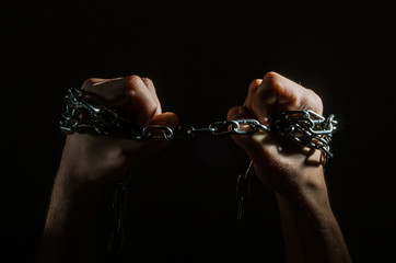 Hands are chained in chains isolated on black background