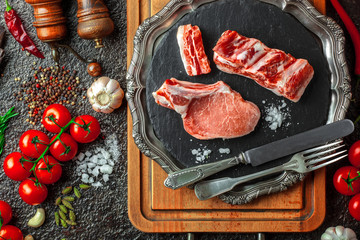 Raw meat on the kitchen table on a metallic background in a composition with cooking accessories