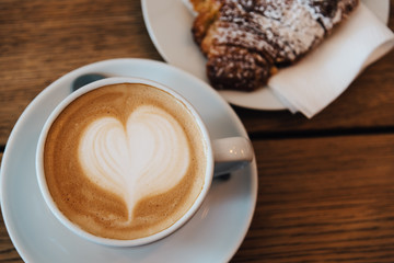Coffee with latte art heart and fresh baked croissant