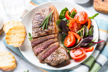 Grilled beef striploin steak with fresh salad.