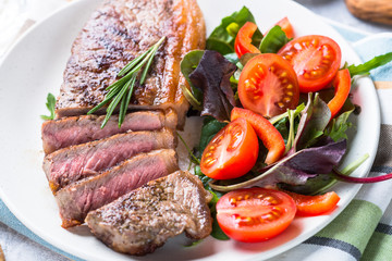 Grilled beef striploin steak with fresh salad.
