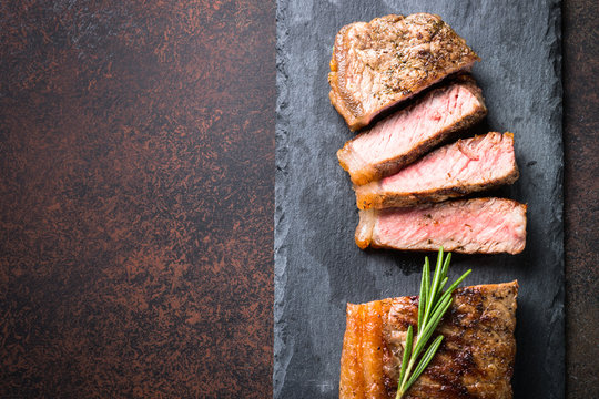 Beef steak. Striploin steak on dark stone table. Top view.
