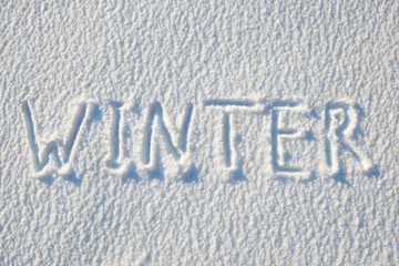 Winter text written on snow for texture or background - winter holiday concept. Sunny day, bright light with shadows, flat lay, top view, clean and nobody