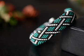 Green bead crochet bracelet with celtic print on a dark background close up