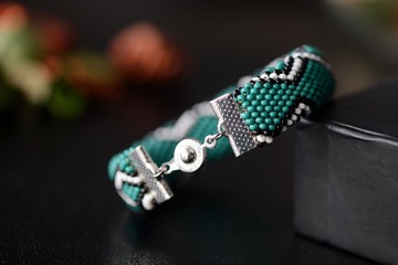 Green bead crochet bracelet with celtic print on a dark background close up