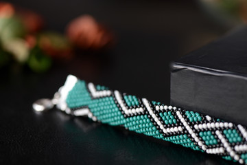 Green bead crochet bracelet with celtic print on a dark background close up