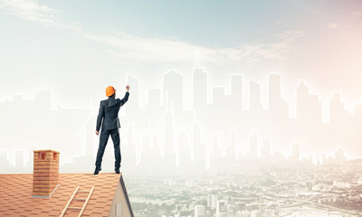 Man architect draw silhouette of modern city on blue sky. Mixed 