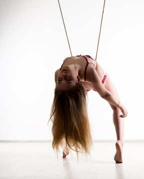 Perfect slim girl with a rope posing on a light background. Sexy athletic body
