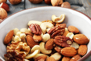 bowl with mixed nuts on wooden background. Healthy food and snack. Walnut, pecan, almonds, hazelnuts and cashews.