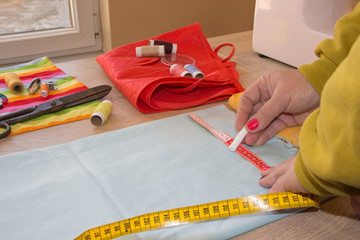 Tailor hands working with measure. Dressmaker cuts dress detail on the sketch lines