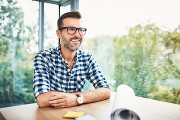 Happy designer sitting at desk in modern office