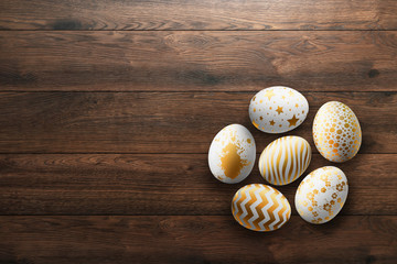 Happy Easter, painted Easter eggs on a wooden background. White gold pattern.
