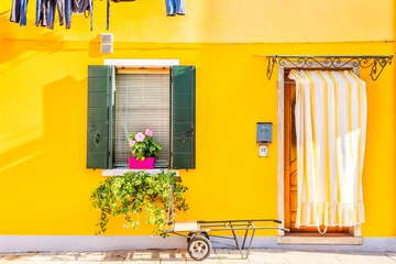 Foto auf Acrylglas Yellow house with flowers and plants. Colorful houses in Burano island near Venice, Italy. © Nikolay N. Antonov