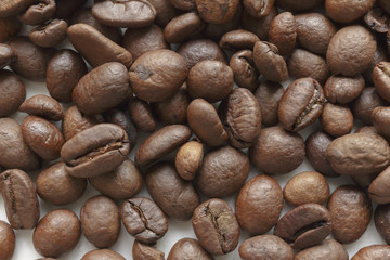 Coffee beans of light roast on white background. Texture of roasted coffee in beans.