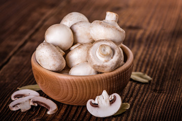 champignons white mushrooms in wooden bowl on wood table background