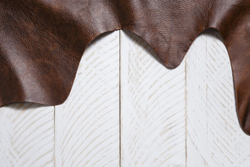 Natural brown cow leather on the white wooden boards. May used as background. Space for text