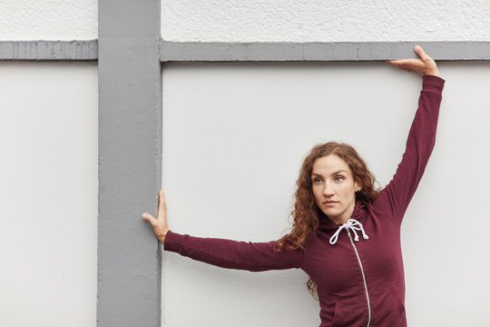 Young woman stretching outdoors against wall