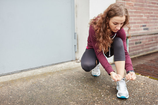 Weiblicher Jogger bindet sich die Laufschuhe