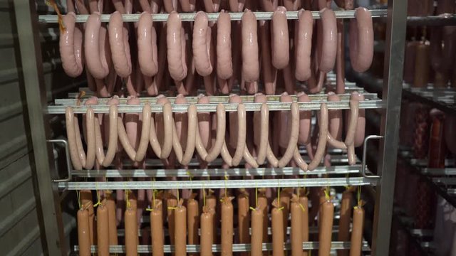 Industrial sausages production process at meat and sausage making plant. Sausage production line. Sausages on racks prepared for smoking.