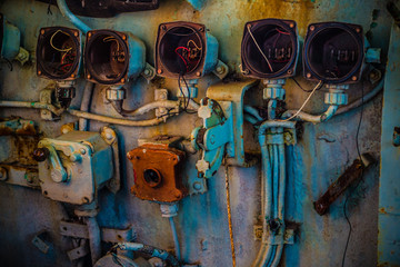Broken and very old circular gauge and controller with lever handle inside the cockpit of abandoned navy ship. © Teeranon