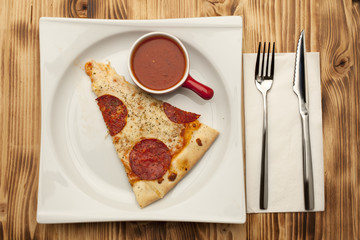 a piece of pizza Peperone on a plate served with ketchup