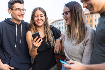 Teen friends with smartphones laughing and having fun