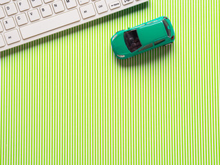 Green background with keyboard and toy car as travelling symbol or car related shopping