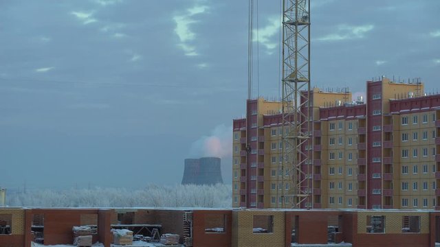time lapse view of industrial urban background in winter in the evening. Industrial landscape with smokestacks pollute atmosphere in the background the construction of a crane. 4 k. time lapse
