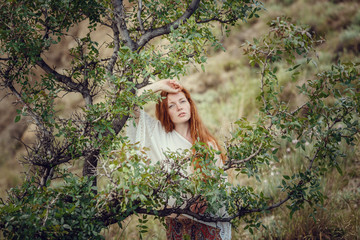 Young red-haired girl in the style of Boho. Enjoys the beauty of the sea coast. The idea and concept of freedom and hippies