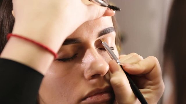 makeup artist creates the shape of the eyebrows for the model
