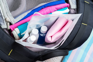 Set of travel bottles and towel in plastic bag