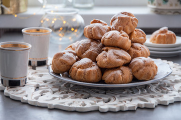 On the table there is a plate of profiteroles, a sweet dessert for breakfast