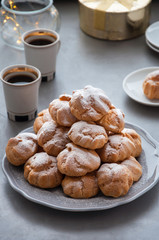 On the table there is a plate of profiteroles, a sweet dessert for breakfast