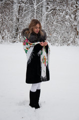 Smiling woman in traditional Ukrainian scarf walking in winter forest